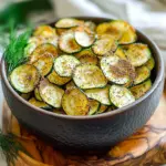 To make Air Fryer Everything Bagel Zucchini Chips, you will need these simple ingredients: - 2 medium zucchinis - 2 tablespoons olive oil - 2 tablespoons everything bagel seasoning - 1 teaspoon garlic powder - 1 teaspoon onion powder - Salt and pepper to taste Each ingredient plays a key role in the flavor and texture of your chips. First, the zucchinis provide a fresh base. They are low in calories and full of nutrients. The olive oil gives the chips a nice crispiness. It also helps the spices stick to the zucchini slices. Everything bagel seasoning brings a blend of flavors. It includes sesame seeds, poppy seeds, garlic, and onion. This mix adds a unique taste that makes these chips special. Garlic powder and onion powder enhance the seasoning, giving more depth. Finally, salt and pepper finish off the flavor profile. Using fresh ingredients will give the best results. Make sure your zucchinis are firm and free from blemishes. This choice helps create a better crunch. You can also adjust the amount of seasoning to fit your taste. If you love garlic, add more garlic powder. If you prefer a bit of heat, try some red pepper flakes. - Wash and dry zucchinis - Slice zucchinis into ¼ inch rounds First, I wash the zucchinis well under cool water. It’s important to remove any dirt. After washing, I pat them dry with a clean towel. Next, I slice each zucchini into thin rounds. I aim for about ¼ inch thick. This thickness helps them crisp up nicely in the air fryer. - Combine zucchini slices with olive oil - Add seasonings and toss In a large bowl, I add the zucchini slices. I drizzle two tablespoons of olive oil over them. Then, I use my hands to toss the slices, making sure each one is coated. After that, I sprinkle everything bagel seasoning, garlic powder, onion powder, salt, and pepper on top. I toss everything again so the spices stick well to each slice. - Preheat air fryer - Cook zucchini chips and shake basket halfway through Now, I preheat my air fryer to 375°F (190°C). This step takes about 3-5 minutes. Preheating helps the zucchini chips cook evenly. After preheating, I place the seasoned zucchini slices in the air fryer basket. I lay them in a single layer. Avoid overcrowding the basket for the best results. I cook the zucchini chips for 10-12 minutes. I check them halfway through and shake the basket. This helps all sides get crispy. Once they are golden brown and crunchy, I take them out. I let them cool for a few minutes as they will get even crispier. To get the best chips, slicing is key. Make each zucchini slice about ¼ inch thick. This thickness helps the chips cook evenly and get nice and crispy. If they are too thick, the chips may turn out soggy. Avoid overcrowding your air fryer basket. Lay the slices in a single layer. Too many slices at once will block air from circulating. This can lead to uneven cooking. If you have a lot of zucchini, cook in batches. This makes a big difference in crispiness. You can adjust the seasonings to suit your taste. Try adding a pinch of cayenne pepper for some heat. Or, mix in some grated Parmesan for a cheesy twist. Get creative with your flavors! When serving, pair these chips with dips. Creamy tzatziki is a great match. Hummus also works well. These dips add a nice contrast to the crunchy chips. Plus, they make snacking even more fun! {{image_4}} You can switch things up with these fun ideas. First, try a spicy everything bagel seasoning. This adds heat and excitement to your chips. You can find spicy blends at stores, or make your own with red pepper flakes. Just mix them with the regular seasoning for a kick. Another tasty option is cheese and herb zucchini chips. Use grated parmesan or cheddar cheese. Add dried herbs like oregano or thyme. This brings a savory twist that cheese lovers will enjoy! If you don’t have an air fryer, don't worry! You can still make zucchini chips. One great method is oven-baking. Preheat your oven to 425°F (220°C). Spread the zucchini chips on a baking sheet. Bake them for 20-25 minutes, flipping halfway through. Watch for that golden brown color. For stovetop frying, heat oil in a skillet. Fry the zucchini slices in batches until they are crispy. Be careful not to overcrowd the pan. This method gives a lovely crunch and a different flavor profile. To keep your leftover chips crispy, store them in a cool, dry place. Avoid putting them in the fridge, as moisture can make them soggy. Instead, use an airtight container or a zip-top bag. If you can, add a paper towel inside to absorb any moisture. This simple trick helps keep your Air Fryer Everything Bagel Zucchini Chips crunchy. When it's time to enjoy your chips again, reheating is key. For the best results, use your air fryer. Preheat it to 375°F (190°C) and place the chips in a single layer. Heat them for about 3-5 minutes. This will bring back their crunch. If you prefer using the oven, preheat it to 350°F (175°C). Spread the chips on a baking sheet in a single layer. Bake for about 5-7 minutes, checking often to avoid burning. Both methods work great to revive your tasty zucchini chips! Yes, you can use many other veggies! Some great options include: - Eggplant - Sweet potatoes - Carrots - Kale These veggies also work well in the air fryer. Just remember to slice them thinly for the best crunch! You can bake zucchini chips in the oven! Here’s how: 1. Preheat your oven to 225°F (110°C). 2. Place zucchini slices on a baking sheet lined with parchment paper. 3. Brush the slices with olive oil and sprinkle seasonings. 4. Bake for about 2 hours. Flip halfway through for even cooking. The chips will be crisp when done. This method takes longer but still gives great results! Store your zucchini chips in an airtight container. They will stay fresh for about 3-5 days. For extra crunch, keep them in a dry place away from moisture. If they lose crunch, just pop them back in the air fryer for a few minutes to revive them! This blog post covered how to make tasty zucchini chips from fresh ingredients. We went through each step, from slicing the zucchinis to seasoning and air frying. You learned tips for crispiness and flavor, plus variations for fun twists. Lastly, we discussed how to store and reheat your chips. Enjoying these healthy snacks is easy and fun. I hope you try this recipe and make it your own!
