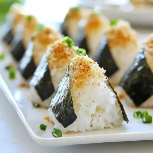- 2 cups sushi rice - 2 ½ cups water - 1 cup cooked chicken breast, shredded - 2 tablespoons soy sauce - 1 tablespoon sesame oil - 1 tablespoon mirin (optional) - 1 teaspoon salt - 4 sheets of nori (seaweed), cut into strips - 1 tablespoon furikake (Japanese rice seasoning) - 1 green onion, finely chopped You can swap sushi rice for short-grain rice. This still gives you a nice texture. If you don’t have chicken, try cooked shrimp or tofu instead. For a vegan option, use soy sauce with no animal products. You can leave out mirin if you want a simpler taste. Substitute the nori with lettuce leaves for a lighter wrap. One serving of chicken onigiri has about: - Calories: 350 - Protein: 20g - Carbohydrates: 50g - Fat: 10g - Fiber: 2g - Sodium: 400mg This meal is a great source of protein and carbs. It gives you energy for the day. Plus, it includes healthy fats from sesame oil. It’s balanced and tasty! {{ingredient_image_2}} First, rinse the sushi rice. Place it in a fine mesh strainer. Run cold water over it. Stir gently with your hand until the water is clear. This step removes extra starch. It helps make the rice fluffy. Next, cook the rice. Combine it with 2 ½ cups of water in a rice cooker. You can also use a pot on the stove. Follow the package instructions for cooking time. Once done, let the rice cool a bit. It should still feel warm. While the rice cools, prepare the chicken filling. In a medium-sized bowl, mix shredded cooked chicken with soy sauce, sesame oil, and salt. If you want, add mirin for extra flavor. Blend these well and let them sit for about 10 minutes. This time allows the flavors to mix better. Once the rice has cooled, dampen your hands with water. This step helps keep the rice from sticking. Take about 1/3 cup of rice and shape it into a ball. Use your fingers to create a small indentation in the center. Spoon a good amount of the chicken mixture into this space. Now, carefully mold the rice around the filling. Shape it into a triangle. Press the rice together gently but firmly to hold the filling inside. Repeat this until all rice and chicken are used. After shaping, sprinkle furikake on each onigiri. This adds a nice burst of flavor. Wrap a strip of nori around the bottom of each triangle. This makes it easy to eat and adds a tasty contrast. Finally, sprinkle chopped green onion on top. It makes the dish look and taste great. When making chicken onigiri, some mistakes can ruin your dish. First, don’t skip rinsing the sushi rice. This step removes excess starch, leading to fluffier rice. Another mistake is packing the rice too tightly. You want a firm shape, but not too tight. This helps keep the onigiri light and airy. Lastly, ensure your chicken filling is seasoned well. A bland filling can make your onigiri boring. To get the best fluffy rice, start with quality sushi rice. Rinse it until the water runs clear. This helps achieve that perfect texture. Use a rice cooker if you have one. It cooks the rice evenly and makes things easy. Let the rice cool a bit before shaping. If it’s too hot, it will stick to your hands. Dampen your hands with water for easy shaping. This keeps the rice from sticking to your fingers. If you have leftover onigiri, store them correctly. Wrap each one in plastic wrap to keep them fresh. Place them in an airtight container. You can keep them in the fridge for up to two days. For longer storage, freeze them. Make sure to wrap them well to prevent freezer burn. To reheat, let them thaw in the fridge overnight. Then, warm them gently in a microwave or steamer. Enjoy your tasty onigiri later! Pro Tips Rinse the Rice: Always rinse sushi rice until the water runs clear to remove excess starch, which helps achieve a fluffy texture. Keep Rice Warm: Shape the onigiri while the rice is still warm for easier molding and better flavor absorption from the filling. Use Wet Hands: Dampen your hands with water while shaping the rice. This prevents the rice from sticking and makes it easier to handle. Experiment with Fillings: Feel free to customize the chicken filling with other ingredients like avocado, pickled vegetables, or tofu for a personal twist. {{image_4}} You can change the filling in onigiri to match your taste. Try using tuna or salmon mixed with mayonnaise for a creamy bite. You can also use vegetables like cucumber or avocado for a fresh taste. For a spicy kick, add sriracha or kimchi to your chicken. If you prefer a vegetarian option, use tofu marinated in soy sauce or a mix of mushrooms. This way, everyone can enjoy onigiri. You can switch up the flavors by changing the seasonings. Instead of soy sauce, try teriyaki sauce for a sweeter flavor. You can also add a bit of garlic or ginger for extra zest. Use miso paste for a rich taste or add a splash of citrus juice like lime or lemon for brightness. Experimenting with different seasonings helps you find your favorite flavor combination. How you serve your onigiri can make it even more fun. Place them on a colorful plate and sprinkle sesame seeds or chopped herbs on top. Serve with small bowls of soy sauce or pickled ginger for dipping. You can also make a fun bento box by adding fruits, nuts, or other snacks alongside your onigiri. This adds variety and makes your meal look appealing. When you make chicken onigiri, you want to keep it fresh. First, let the onigiri cool to room temperature. Place them in an airtight container. This helps keep them from drying out. You can store them in the fridge for up to two days. If you plan to keep them longer, freezing is a better option. In the fridge, onigiri will stay fresh for about two days. Wrap each onigiri in plastic wrap for extra protection. This helps keep the rice soft. For freezing, place the wrapped onigiri in a freezer bag. You can freeze them for up to a month. When you're ready to eat, just take them out and thaw. To reheat onigiri, you can use a microwave. Unwrap them and place them on a microwave-safe plate. Heat for about 30 seconds. Check if they are warm enough. If they need more time, heat in 10-second bursts. Avoid overheating, or the rice may become dry. Enjoy your tasty chicken onigiri again! You can use short-grain rice instead. Short-grain rice gets sticky, which helps the onigiri hold its shape. Just follow the same steps for rinsing and cooking. Yes! You can use cooked beef, pork, or shrimp. Just make sure to season it well. For a vegetarian option, try using tofu or mushrooms. Look for Japanese restaurants or sushi bars. Many places offer onigiri on their menu. You might also find them in Asian grocery stores. In this blog post, we explored how to make onigiri, focusing on ingredients, step-by-step instructions, and helpful tips. I shared how to prepare the rice and create tasty chicken fillings. We also discussed common mistakes and fun variations. Remember to store your onigiri correctly for the best taste. With these insights, you're ready to make delicious onigiri at home. Enjoy your cooking adventure and impress your family and friends with this tasty treat!
